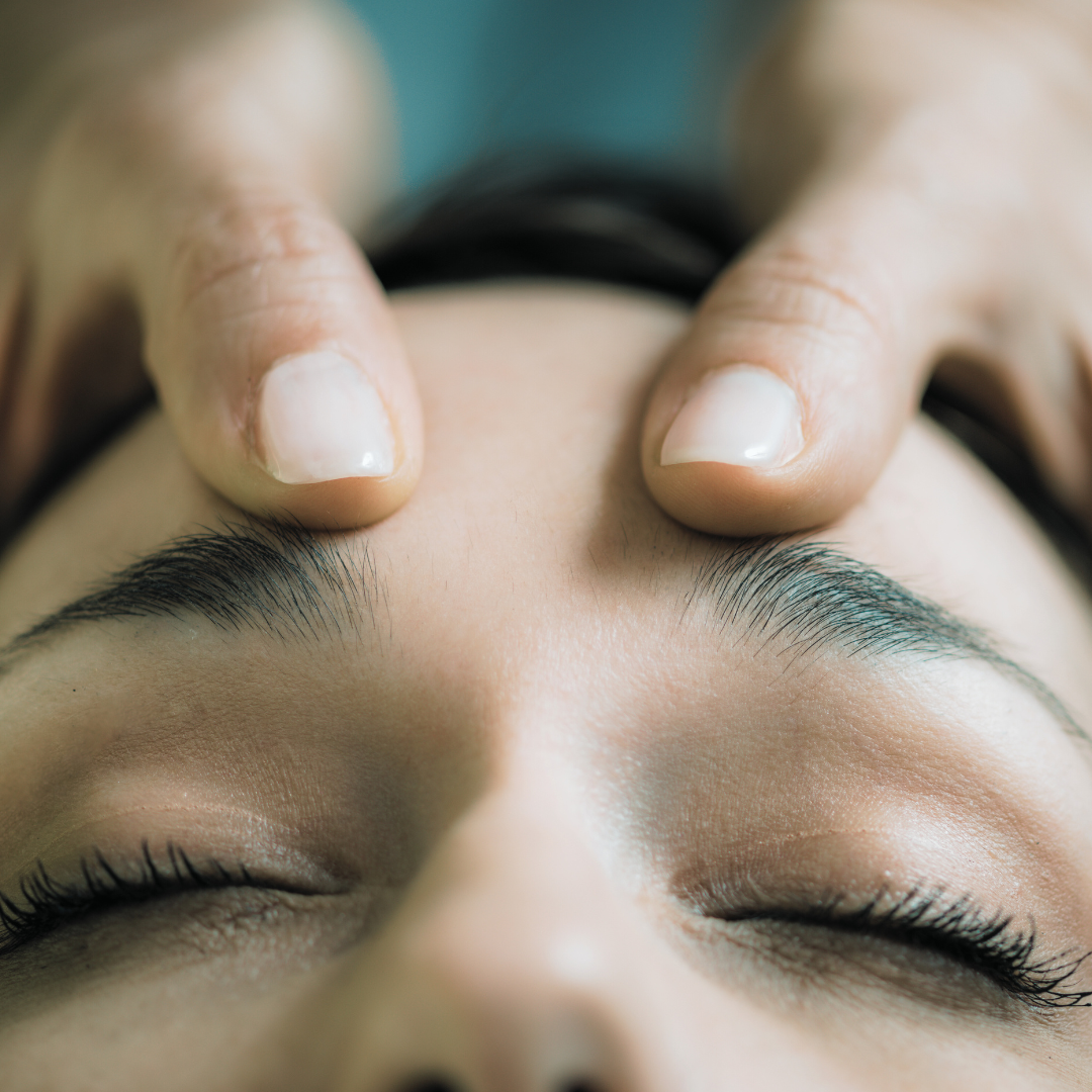 a person's hands massaging their face